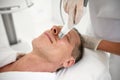 Rejuvenating facial treatment. Mature man getting lifting therapy massage in a beauty SPA salon. Exfoliation, stimulation and Royalty Free Stock Photo