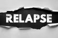 Relapse text on torn paper background. Symbolic concept of recovery setbacks and overcoming personal struggles Royalty Free Stock Photo