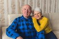 Relationship and companionship. Elderly heterosexual caucasian couple sitting on a couch and looking at camera Royalty Free Stock Photo