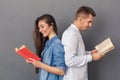 Relationship Concept. Young couple studio standing back to back isolated on grey reading books joyful Royalty Free Stock Photo