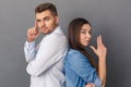 Relationship Concept. Young couple studio standing back to back isolated on grey showing gun gesture looking camera cool Royalty Free Stock Photo