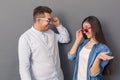 Relationship Concept. Young couple studio standing isolated on grey taking off glasses looking at each other happy Royalty Free Stock Photo