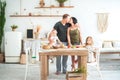 Relationship in the family with small children. Dad and mom kiss in the bright kitchen, children cook in the kitchen Royalty Free Stock Photo