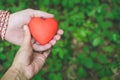 Relationship and love concept - female and male hands holding red heart Royalty Free Stock Photo