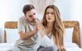 Relationship problems. Husband calms his wife, upset woman rejects boy on bed Royalty Free Stock Photo