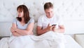 Relationship problems concept - a middle-aged couple lying in bed in the morning a man holding a smartphone. Middle age couple in Royalty Free Stock Photo