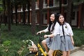 Relax Asian Chinese pretty girls wear student suit in school enjoy free time ride bike in nature spring garden Royalty Free Stock Photo