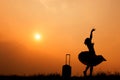 Relax Asian woman with a suitcase on a meadow at sunset silhouette.Holiday travel concept Royalty Free Stock Photo