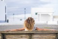 Beautiful curly hair black skin tanned woman viewed from back sitting on a bench