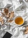 Relax cozy time - cup of green tea, music player headphones in bed. Top view Royalty Free Stock Photo