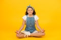 Relax and get comfortable. Small girl sit in yoga posture on yellow background. Little child enjoy yoga training. Yoga