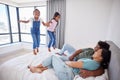 Relax, happy family and kids jump on bed mattress in Philippines home with parents watching. Young, excited and happy Royalty Free Stock Photo