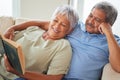 Relax, happy and senior couple reading a book together at home while relaxing and smiling on a couch. Mature or old Royalty Free Stock Photo