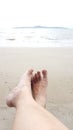 Relax of man feet above the wet beach point to the sea