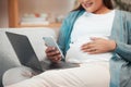 Relax, pregnancy and woman on sofa with phone and laptop in living room at home reading email or text. Internet, video Royalty Free Stock Photo