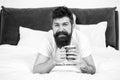 Relax and rest. Full of energy. Coffee affects body. Man handsome hipster relaxing on bed with coffee cup. Bearded