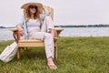 Relax and restore the calm. a beautiful young woman relaxing on a chair next a lake.