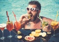 Relax at sea and spa resort. Cocktail with fruit at bearded man in pool. Pool party, vitamin and dieting. Man swimming
