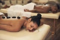 Relax while we soothe those tired muscles. a young woman getting a hot stone massage at a spa. Royalty Free Stock Photo