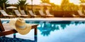 Relax in style: a straw hat and a sun lounger that floats right into the blue water of a modern hotel pool - Generative AI