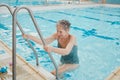 Relax, summer and health with old woman in swimming pool for training, cardio and exercise. Wellness, retirement and