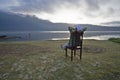 Relax woman sitting on a chair with hands on head and relax legs enjoying calm lake in the morning. Inspirational backgrounds. Royalty Free Stock Photo