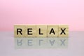 Relax word made of wooden letters on a pink background