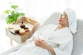 Relax young Asian woman in bathrobe, towel on a head, lying on the sofa bed with sliced cucumbers on her eyes and beauty treatment Royalty Free Stock Photo