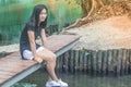 Relaxation Concept : Woman wear white sneaker and sitting on wooden bridge above the river. Royalty Free Stock Photo