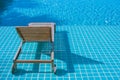 Wooden daybed setting on mosaic tiles in swimming pool at the resort.