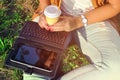 Relaxation with a cup of coffee and tablet.Girl with laptop an coffee. Beautiful young woman with notebook sitting on the grass. Royalty Free Stock Photo