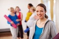 Relaxation exercise in perfect for pregnancy. A young pregnant woman standing in a gym holding an exercise mat with a