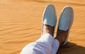 Relaxation. A gentleman`s legs crossed in the desert sand.