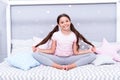 Relaxation and meditation. Girl child sit on bed in her bedroom. Kid prepare to go to bed. Pleasant time for evening