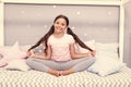 Relaxation and meditation. Girl child sit on bed in her bedroom. Kid prepare to go to bed. Pleasant time for evening Royalty Free Stock Photo