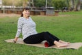 Relaxation after workout. Happy adult sportive woman in casual sportswear works out the fascia of the back muscles of