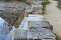 The relaxation zone by the water of the pond with a stone staircase in the park is a stepped stone path made of beige sandstone. i