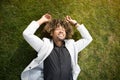 Relaxed african american man entrepreneur lying on green grass on lawn and relaxing during break from work in park Royalty Free Stock Photo