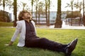 Relaxed african american middle aged businessman resting and sitting on grass in park, feeling free, escaping from work Royalty Free Stock Photo