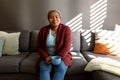 Relaxed african american senior woman sitting on sofa and drinking coffee