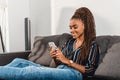 relaxed african american woman using smartphone on couch