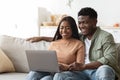 Relaxed african american young couple enjoying weekend together, using laptop Royalty Free Stock Photo