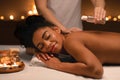 Relaxed african woman enjoying aromatherapy and massage at spa Royalty Free Stock Photo