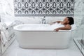 Relaxed african woman taking bath with foam with pleasure, enjoying spa, hygiene Royalty Free Stock Photo