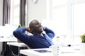 Relaxed Afro American business man sitting at his desk looking into the air. Royalty Free Stock Photo