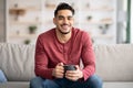 Relaxed arab guy sitting on couch and drinking tea