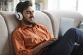 Relaxed arab guy watching movile on laptop, home interior Royalty Free Stock Photo