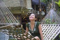 Relaxed Asian Chinese woman on her 20s wearing green Summer dress sitting happy joyful and comfortable on beautiful hammock bed Royalty Free Stock Photo