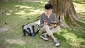 Relaxed Asian male college student eating apple while reading a book under the tree Royalty Free Stock Photo