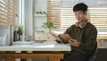 Relaxed asian male freelancer resting from work and reading book Royalty Free Stock Photo